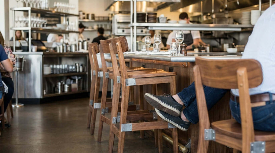 Alt Tag: Restaurant counter with wooden stools and footrests, highlighting bar stool footrest safety and stability for comfortable seating