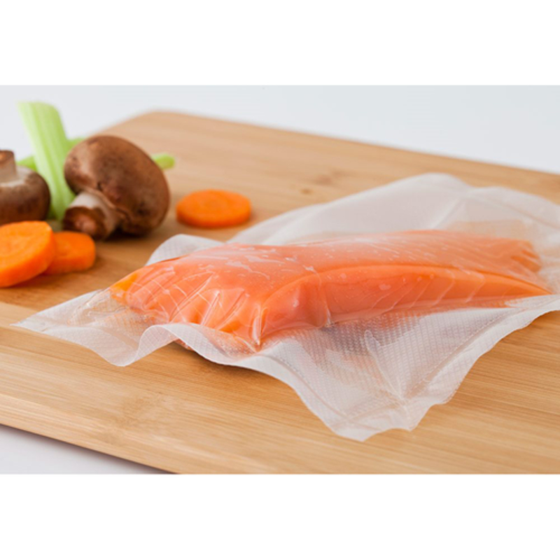 Sachets sous vide embossés ATMOVAC CB100 pour la conservation des aliments, scellant le filet de saumon frais sur une planche à découper pour congélation et sous vide