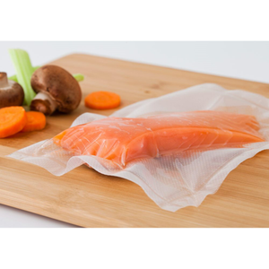 Salmon Fillet Sealed in ATMOVAC Channeled Vacuum Sealer Bags on a Wooden Cutting Board with Fresh Vegetables