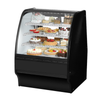 Curved Glass Refrigerated Bakery Case Displaying Assorted Cakes And Pastries In A Stylish Black Showcase.